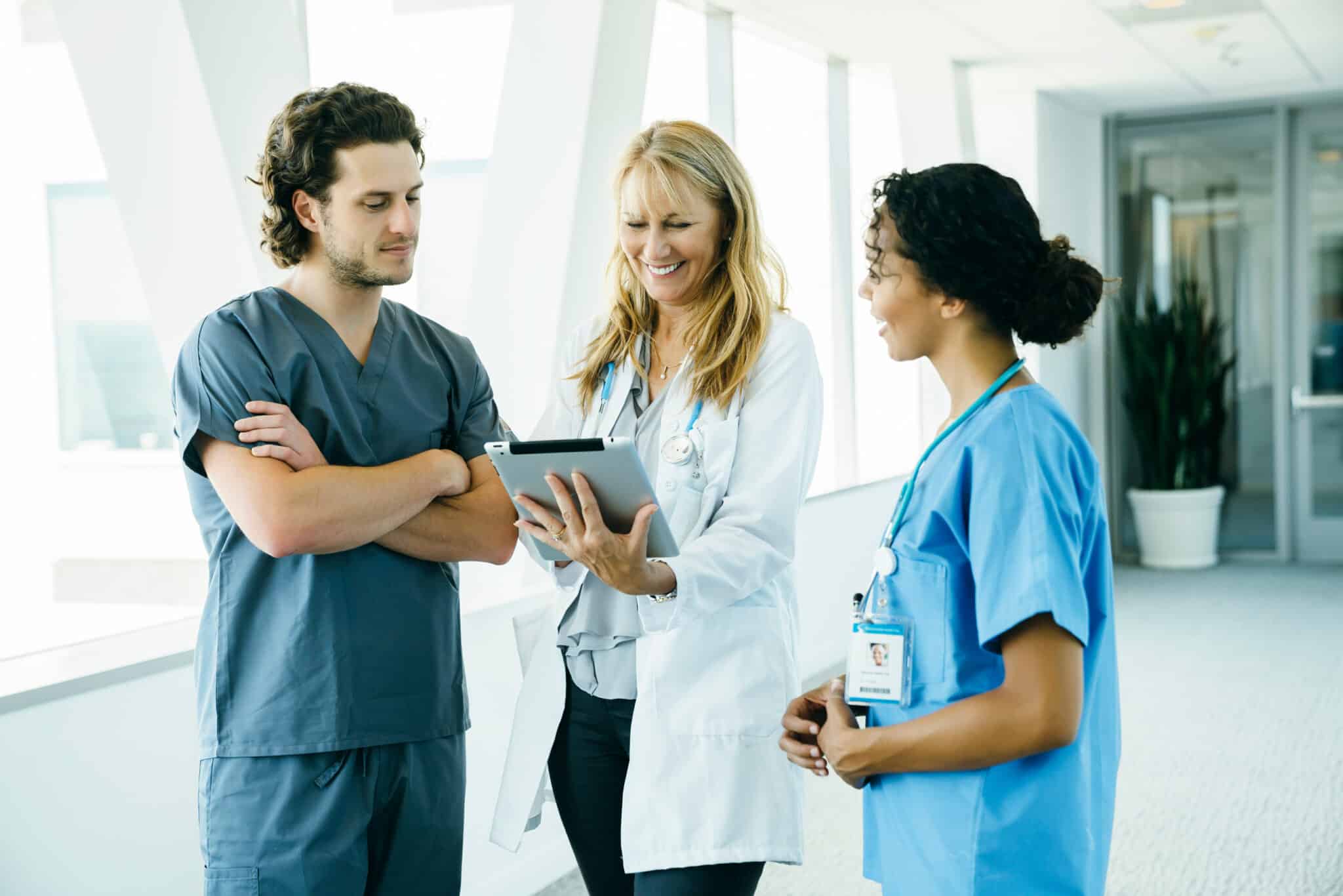 Hospital medical staff assesses records on a tablet, aided by medical transcription outsourcing.