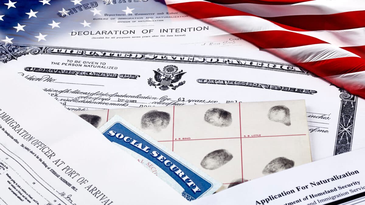 Stack of immigration documents appear next to a U.S. flag, representing U.S. immigration law.