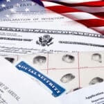 Stack of immigration documents appear next to a U.S. flag, representing U.S. immigration law.