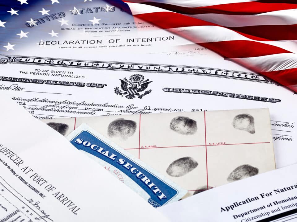 Stack of immigration documents appear next to a U.S. flag, representing U.S. immigration law.