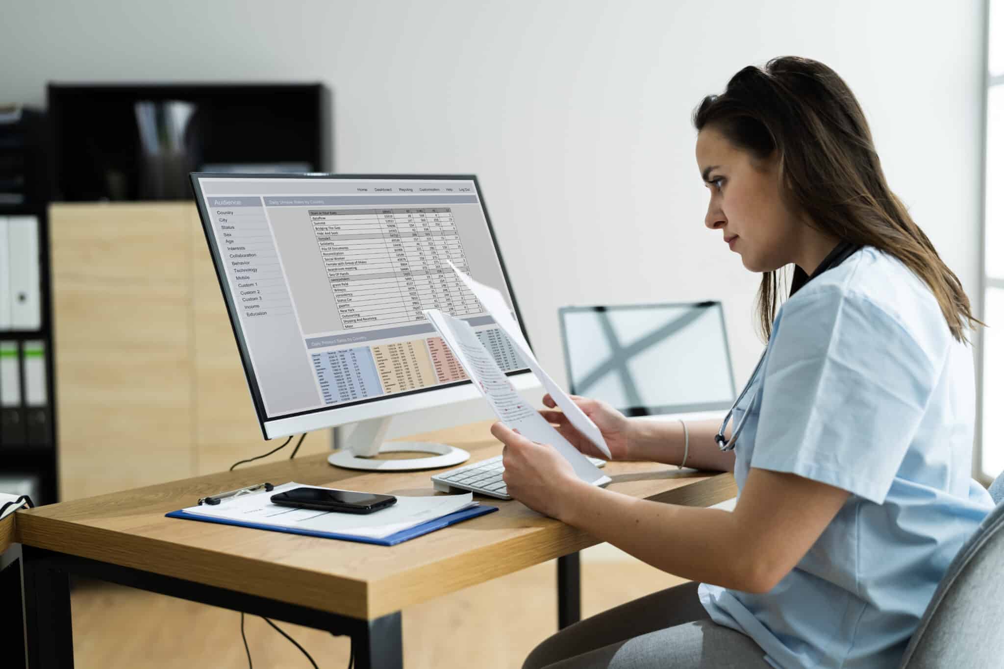 Woman at desk reviewing medical reports and billing codes from a medical transcription company.