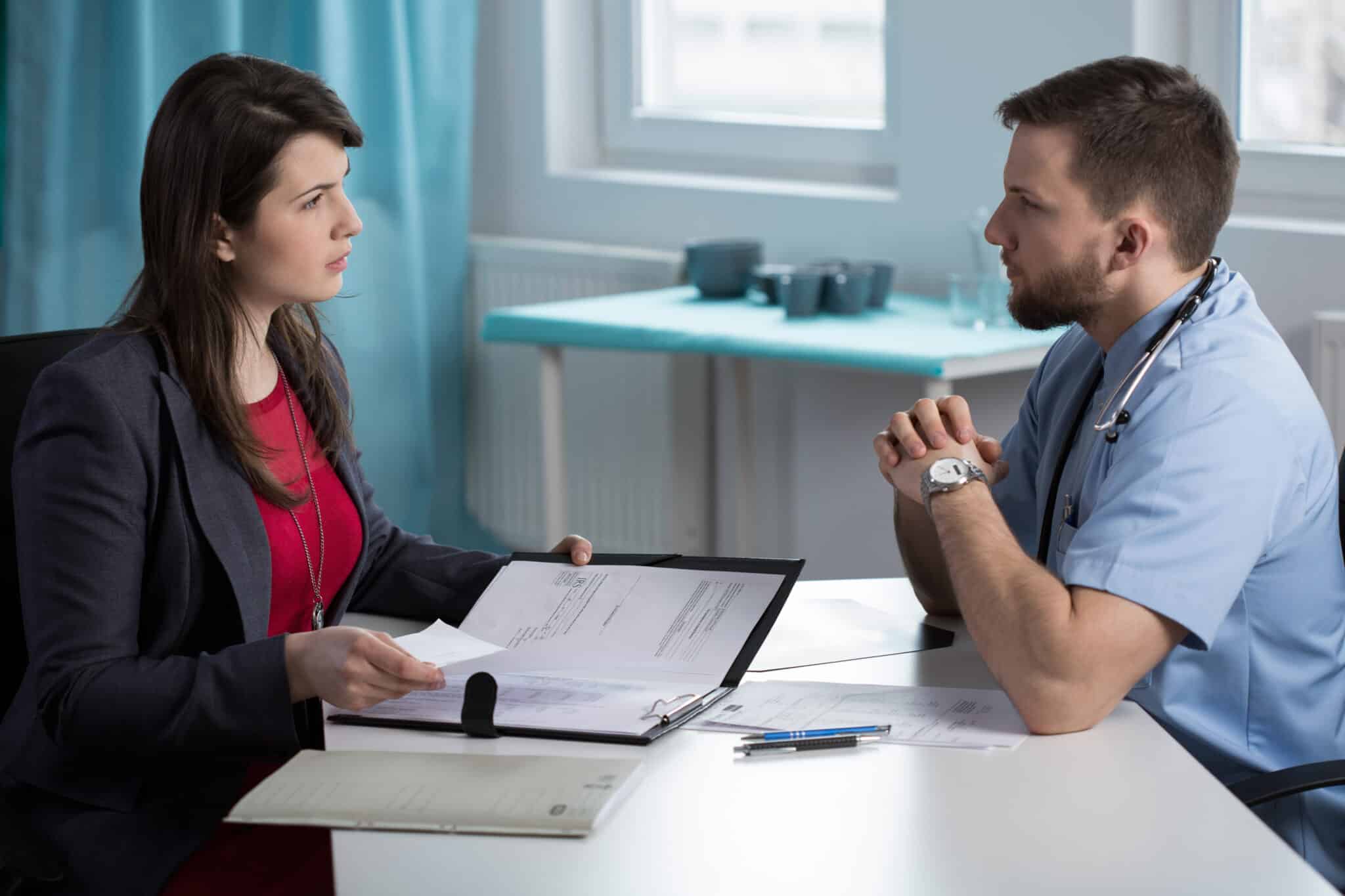 Lawyer and doctor in serious meeting discuss a malpractice claim related to medical record errors.