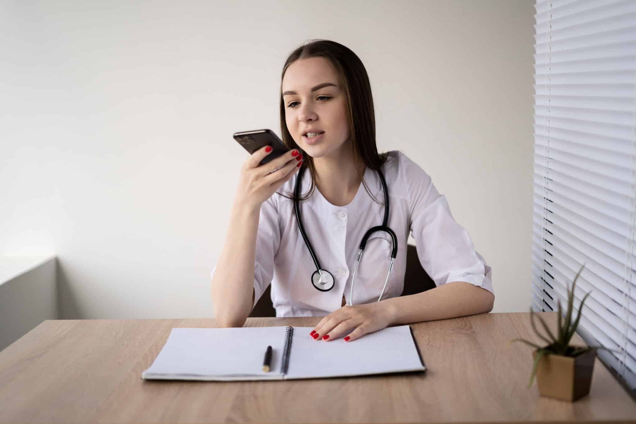 Physician using a mobile device to dictate medical notes in a quiet room for clinical documentation.