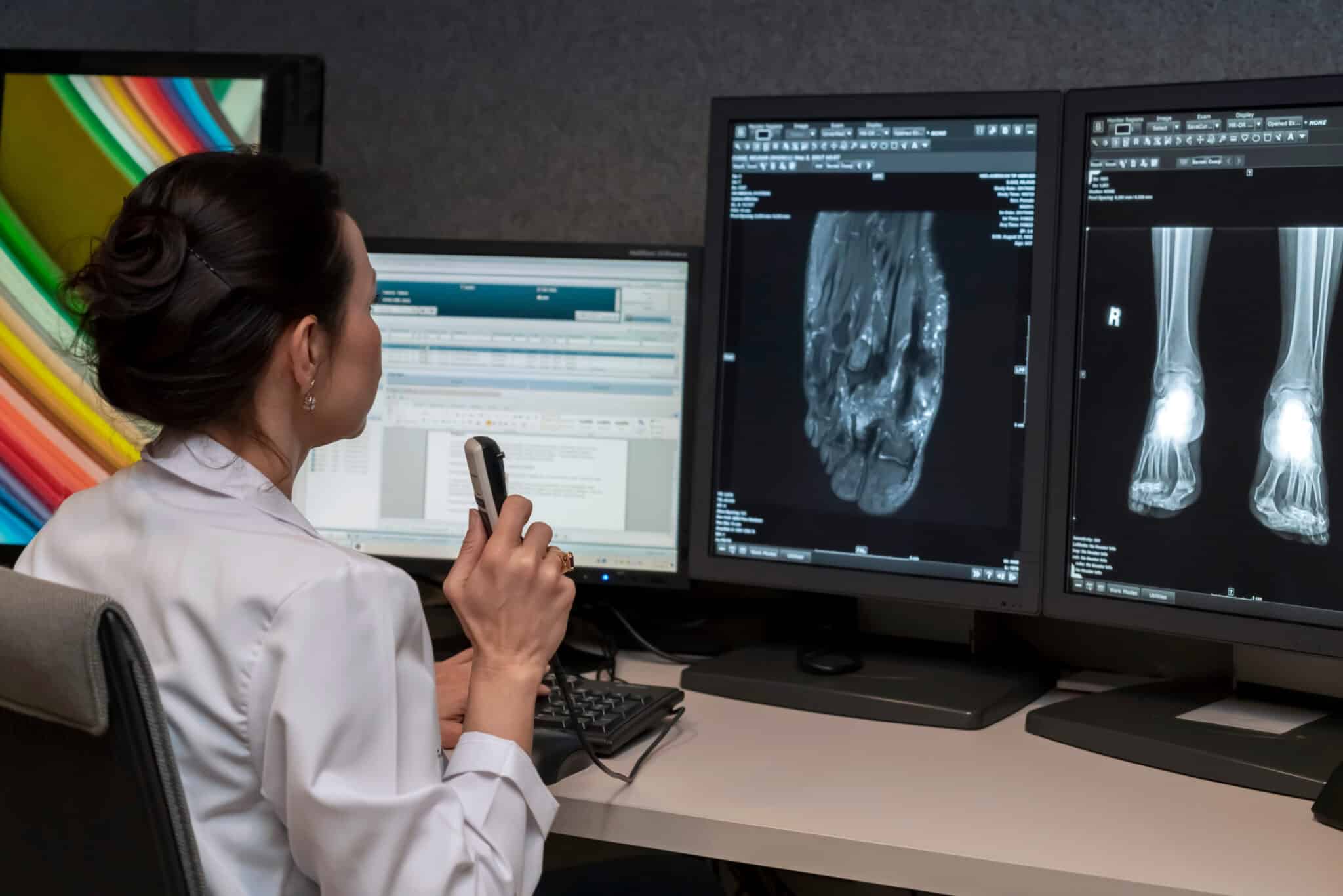 Radiologist at workstation, using speech recognition software to dictate diagnostic notes.