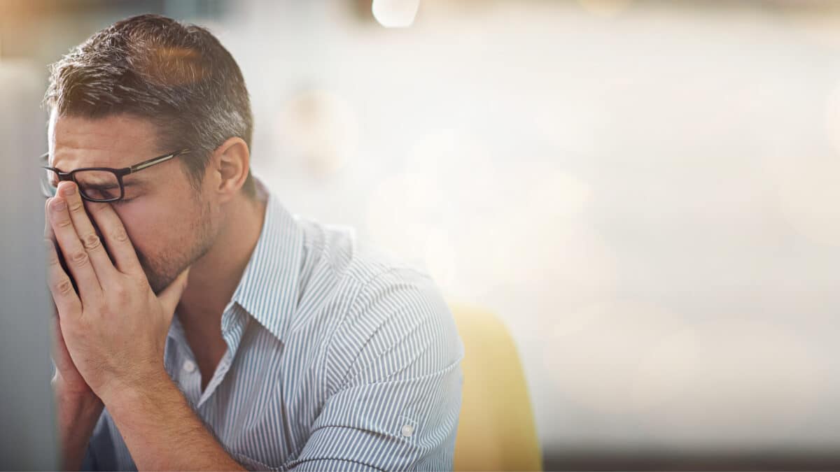 Bank manager rubs his eyes from being tired and overworked. Transcription can ease his workload.