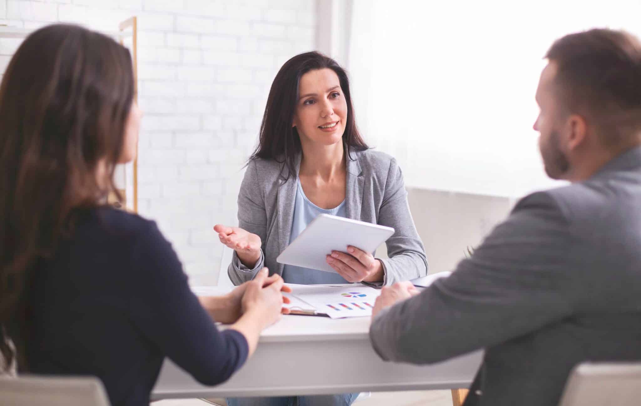 Financial advisor talks to couple and uses a tablet to record their conversation for transcription.