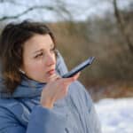 Insurance adjuster uses smartphone to dictate field notes for transcription outdoors at claim site.