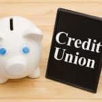 Piggy bank on a desk with 'Credit Union' sign, symbolizing transcription services in credit unions.