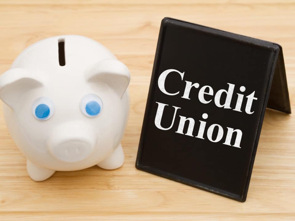 Piggy bank on a desk with 'Credit Union' sign, symbolizing transcription services in credit unions.