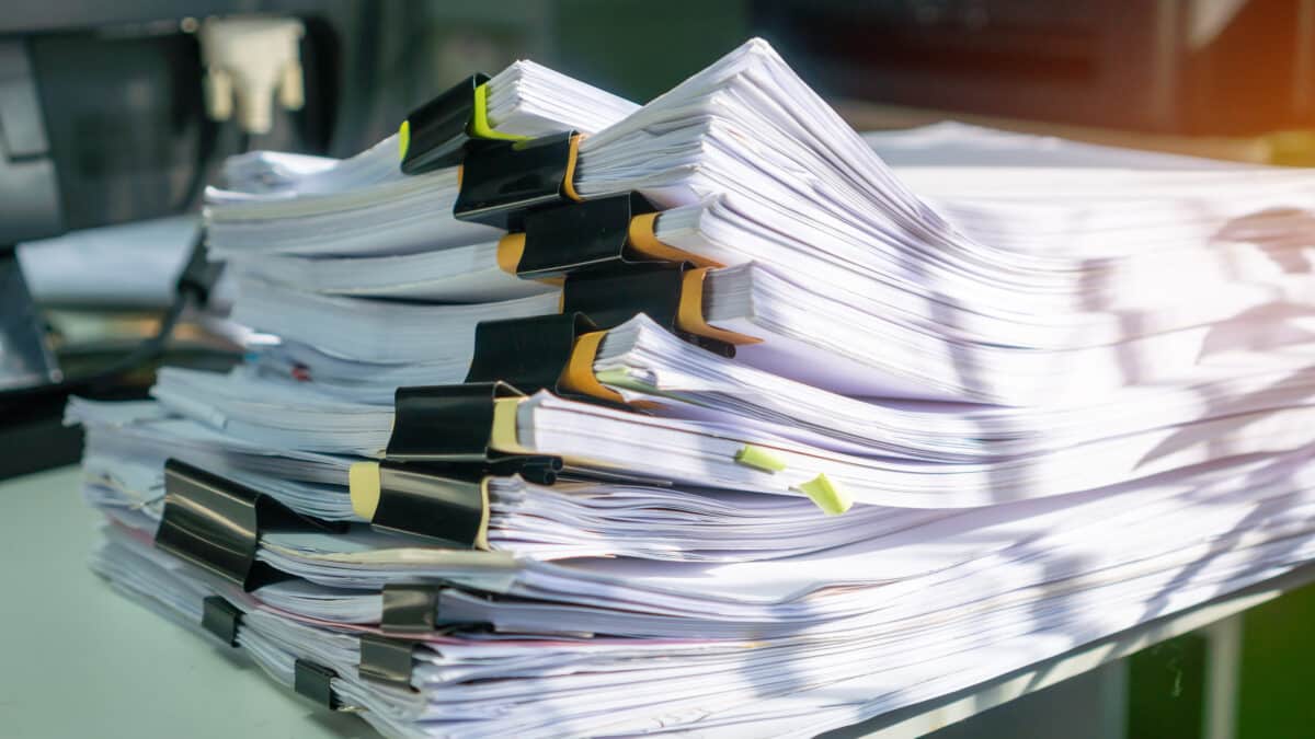 Stack of insurance documents on a desk, representing the need for efficient speech-to-text services