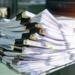 Stack of insurance documents on a desk, representing the need for efficient speech-to-text services