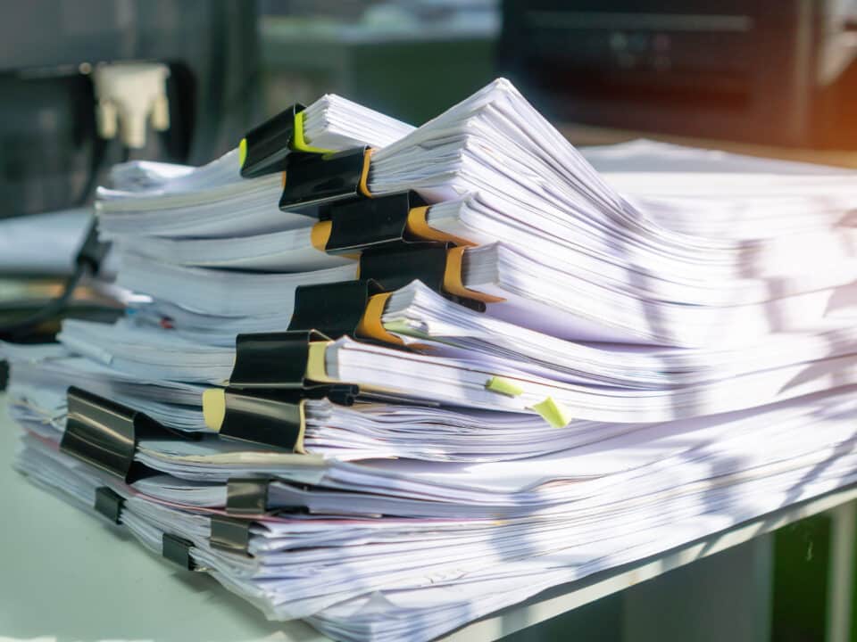 Stack of insurance documents on a desk, representing the need for efficient speech-to-text services