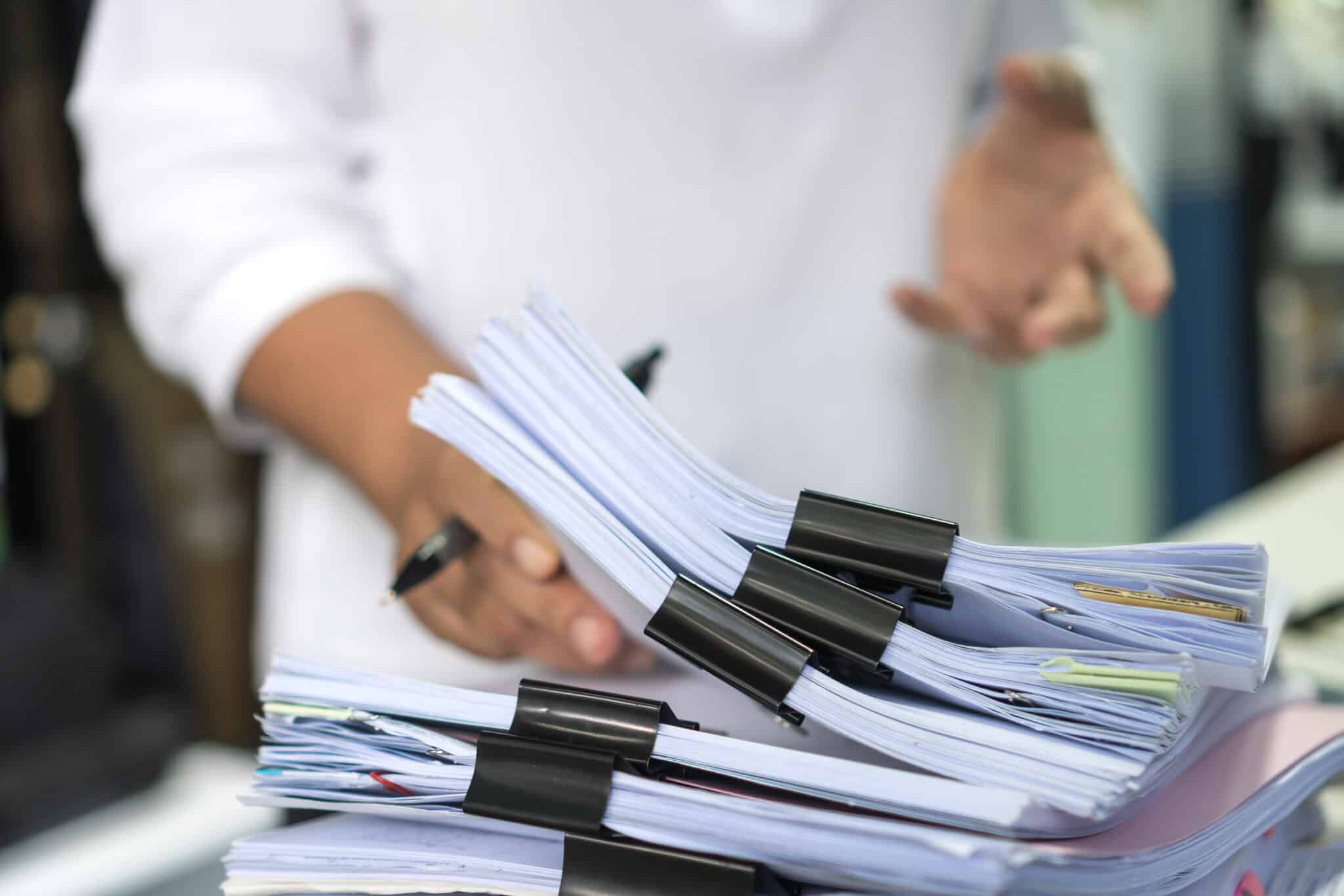 Worker sorts stacks of insurance documents, denoting transcription's importance in file organization