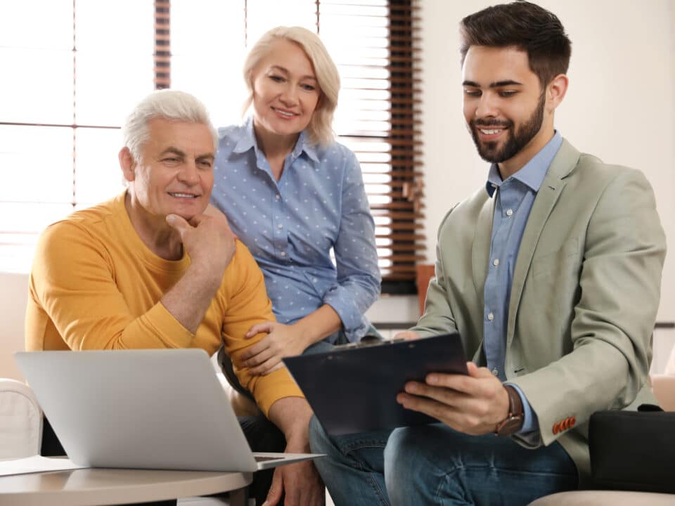 Male financial advisor with mature couple in office, recording their discussion for transcription.