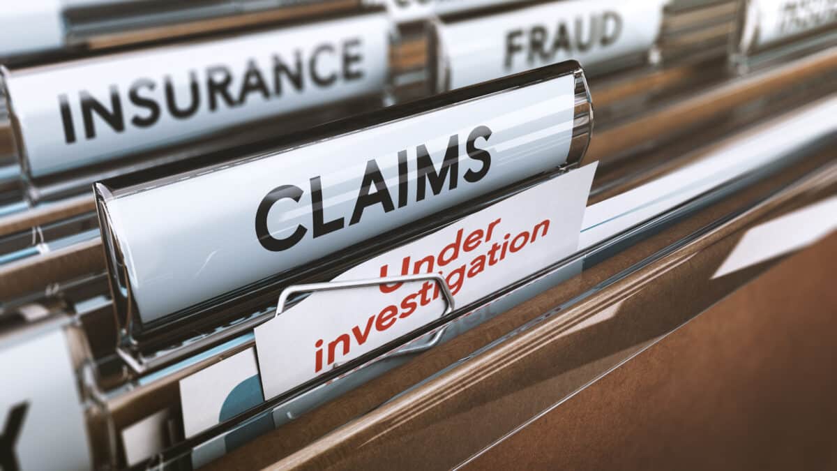 File folders labeled 'Claims' and 'Fraud' in a cabinet, denoting insurance transcription services.