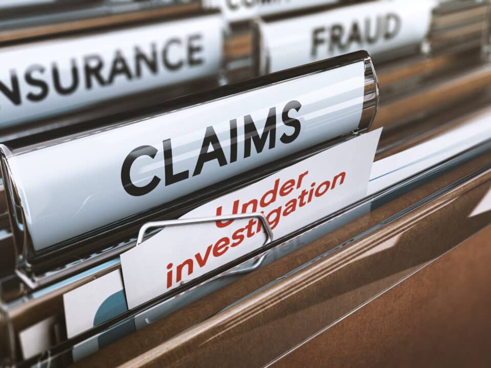 File folders labeled 'Claims' and 'Fraud' in a cabinet, denoting insurance transcription services.