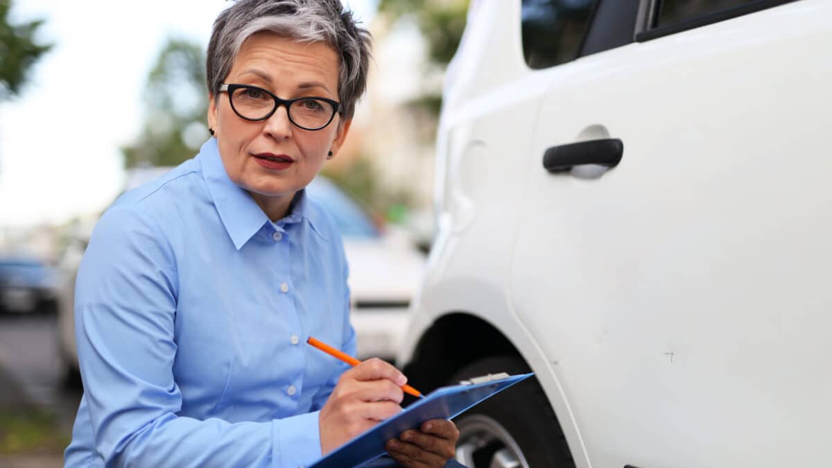 Insurance agent noting car damage, exemplifying the importance of detailed transcription in claims.