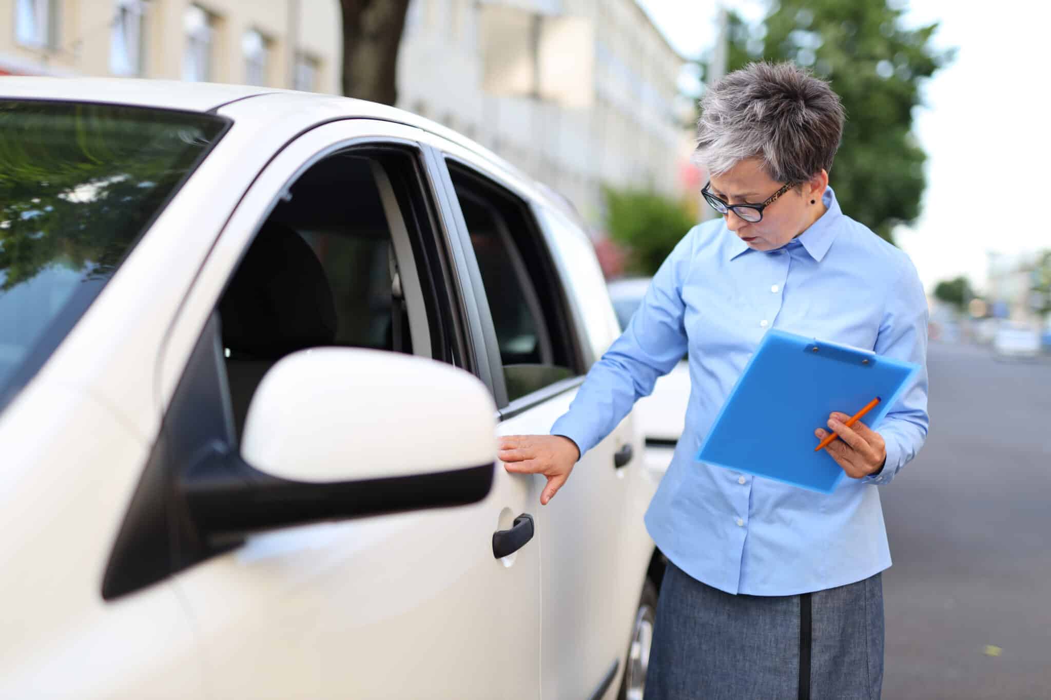 Insurance investigator inspects car accident damage, a scenario where transcription services help.