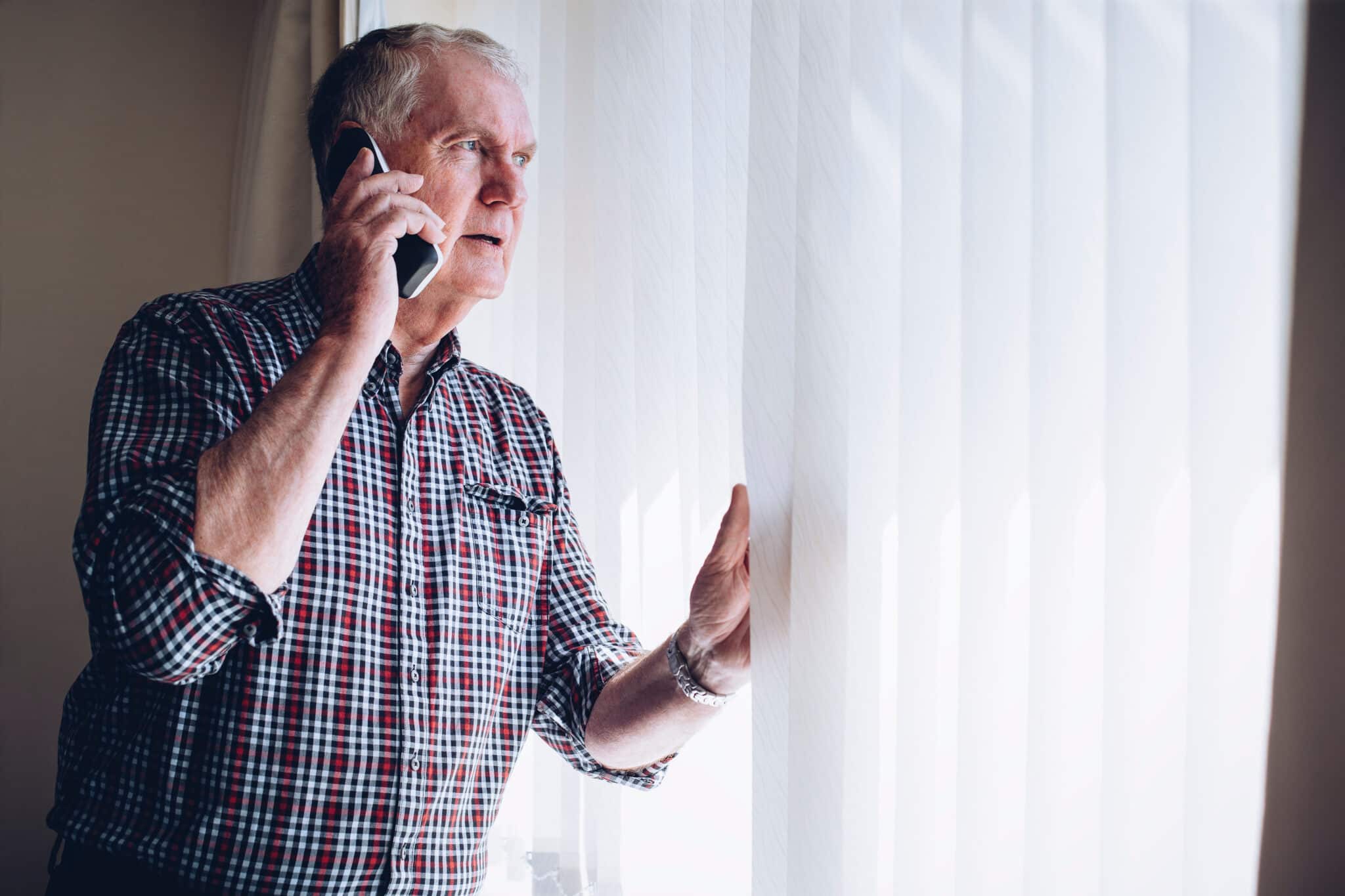 Man on his phone reports a crime looking through window, typical in witness statement transcripts.