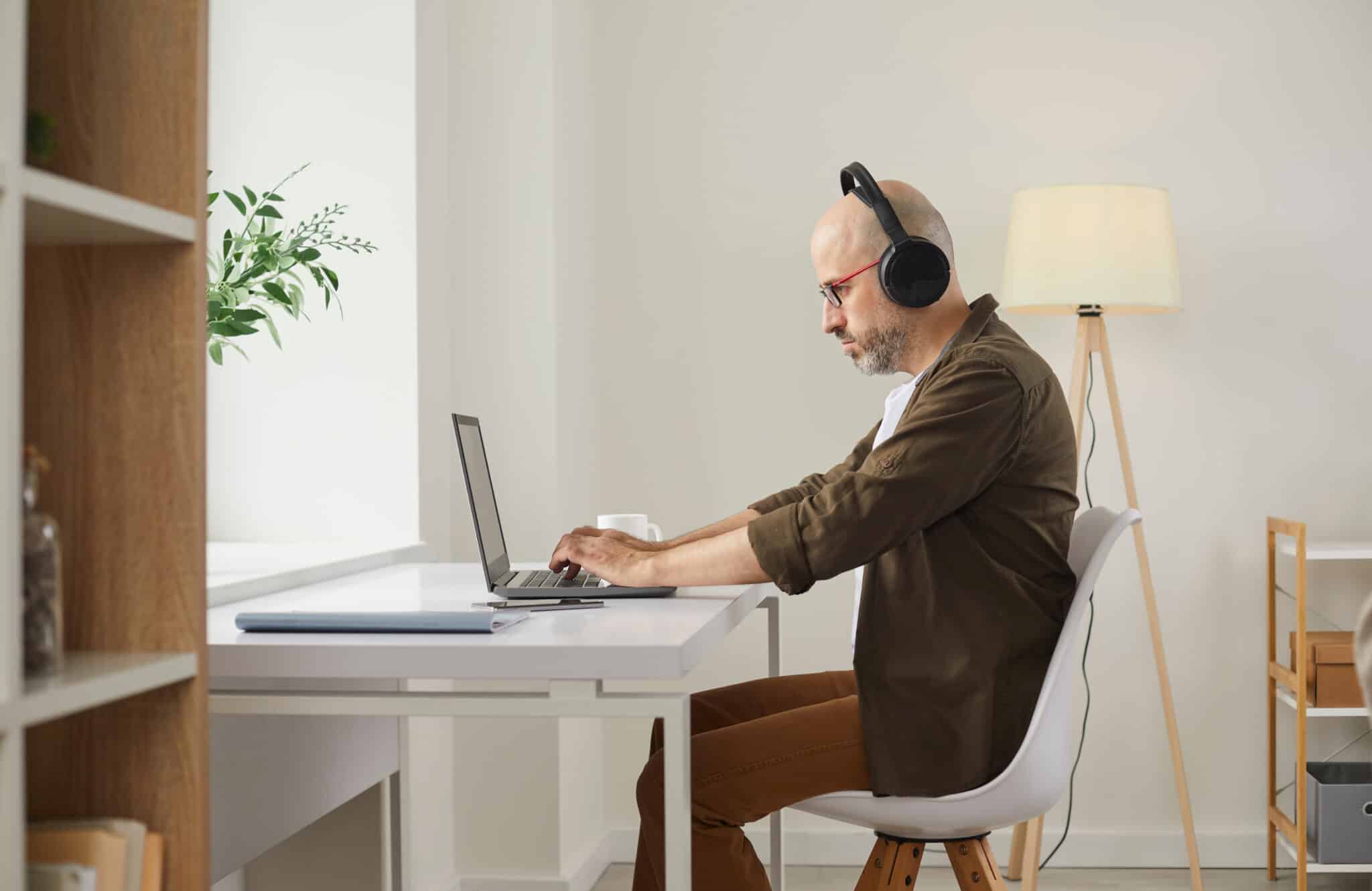 Athreon transcriptionist with headphones focuses on a transcription project on his laptop at home.