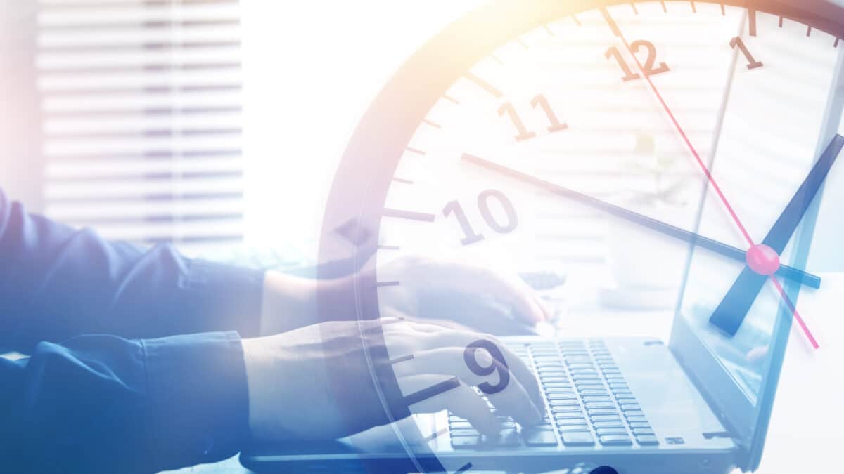 Man typing on computer with clock overlay, illustrating transcription time for 1 hour of audio.