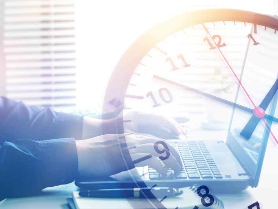 Man typing on computer with clock overlay, illustrating transcription time for 1 hour of audio.