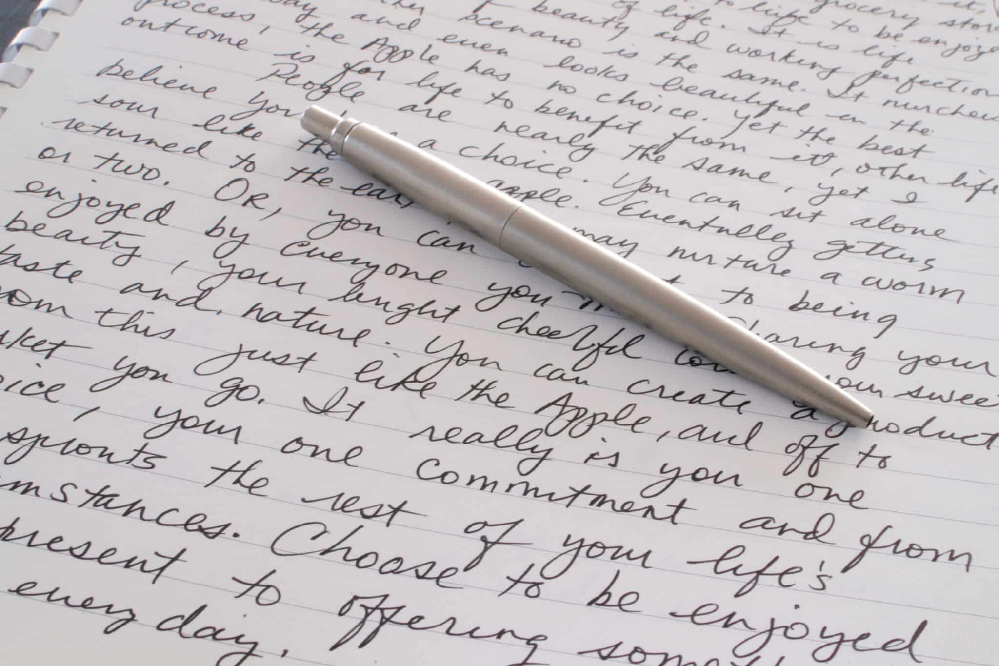 Stainless steel pen on page with text, symbolizes Athreon's transition of written content to digital
