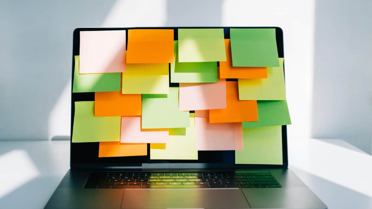 A laptop covered by many sticky notes symbolizes the stress of DIY video transcription efforts.