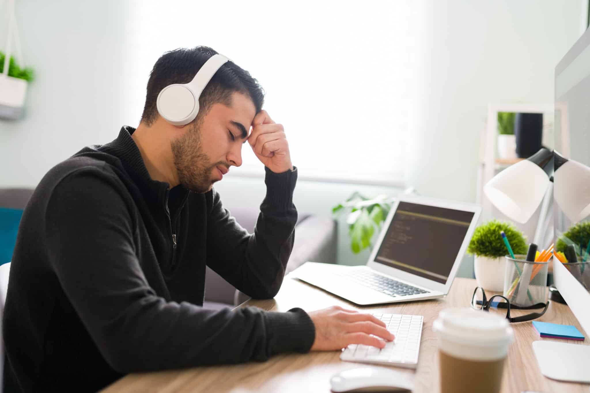 A tired employee overwhelmed by manual video transcription work highlights the need for outsourcing.