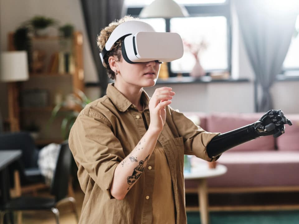 Deaf woman in VR headset uses prosthetic arm and captions in video game.