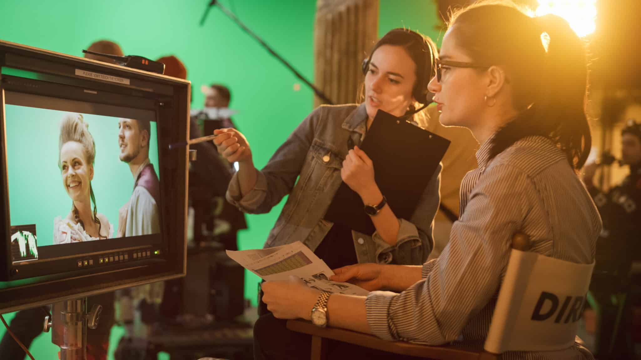 Director consults assistant on green screen set, highlighting transcription services in filmmaking.