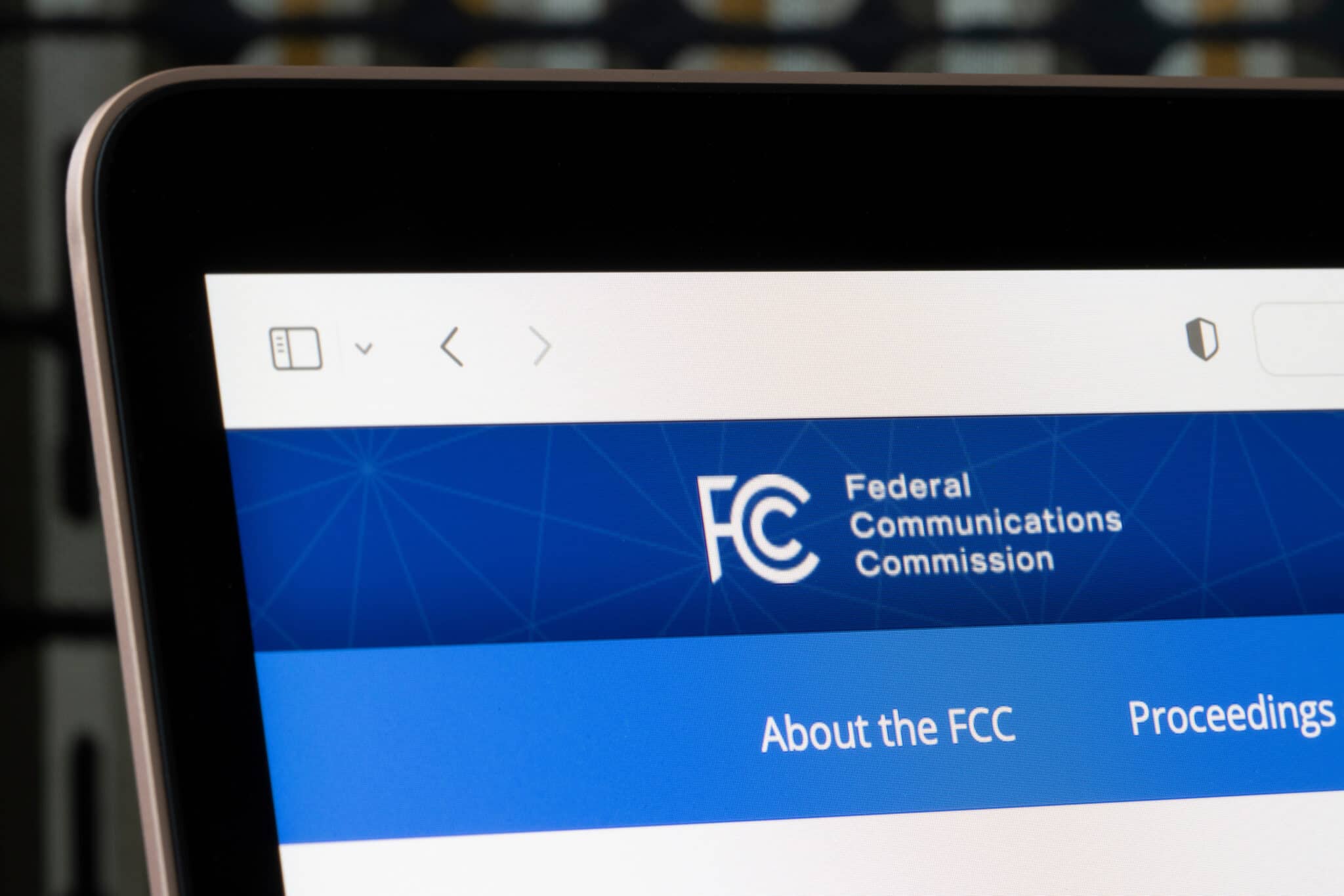 FCC homepage on laptop highlights their regulation of media like TV, relevant to closed captioning.