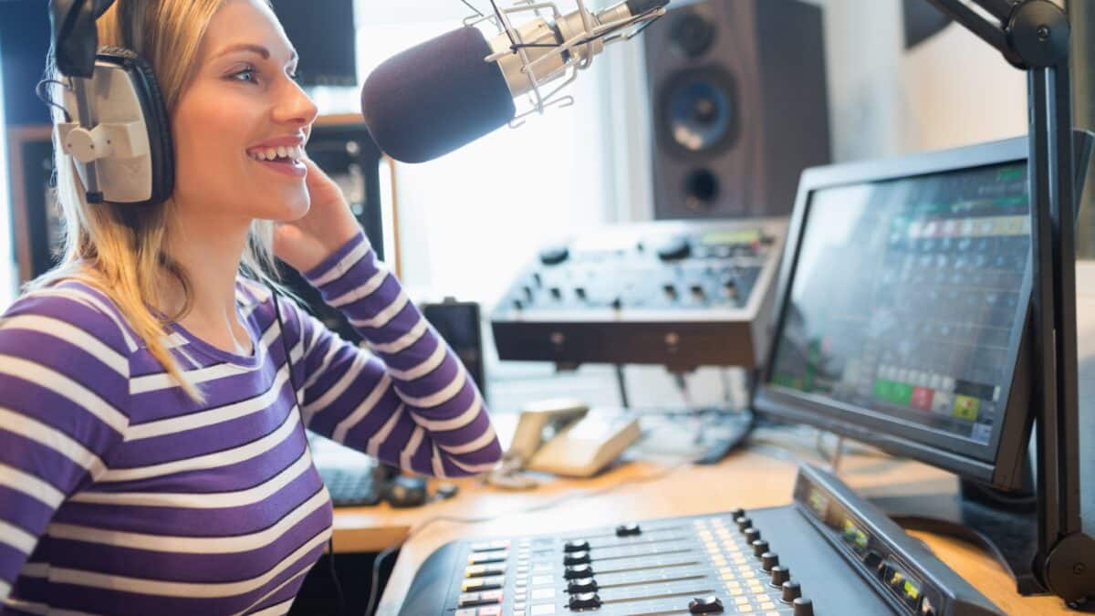 Joyful female radio host live broadcasting, underscoring the value of radio transcription services.