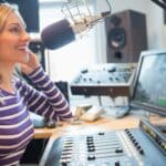 Joyful female radio host live broadcasting, underscoring the value of radio transcription services.