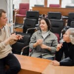 Three deaf students chat in sign language in a classroom, supported by Athreon's captioning service.