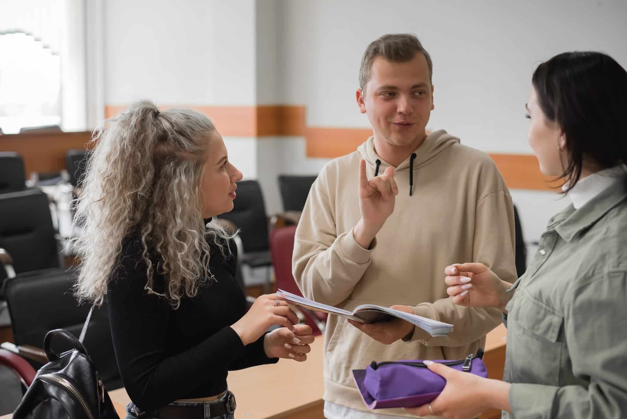 Three deaf students chat in sign language in a classroom, supported by Athreon's captions.