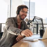 Young male podcaster in a studio session uses transcription services to enhance his podcast's reach.