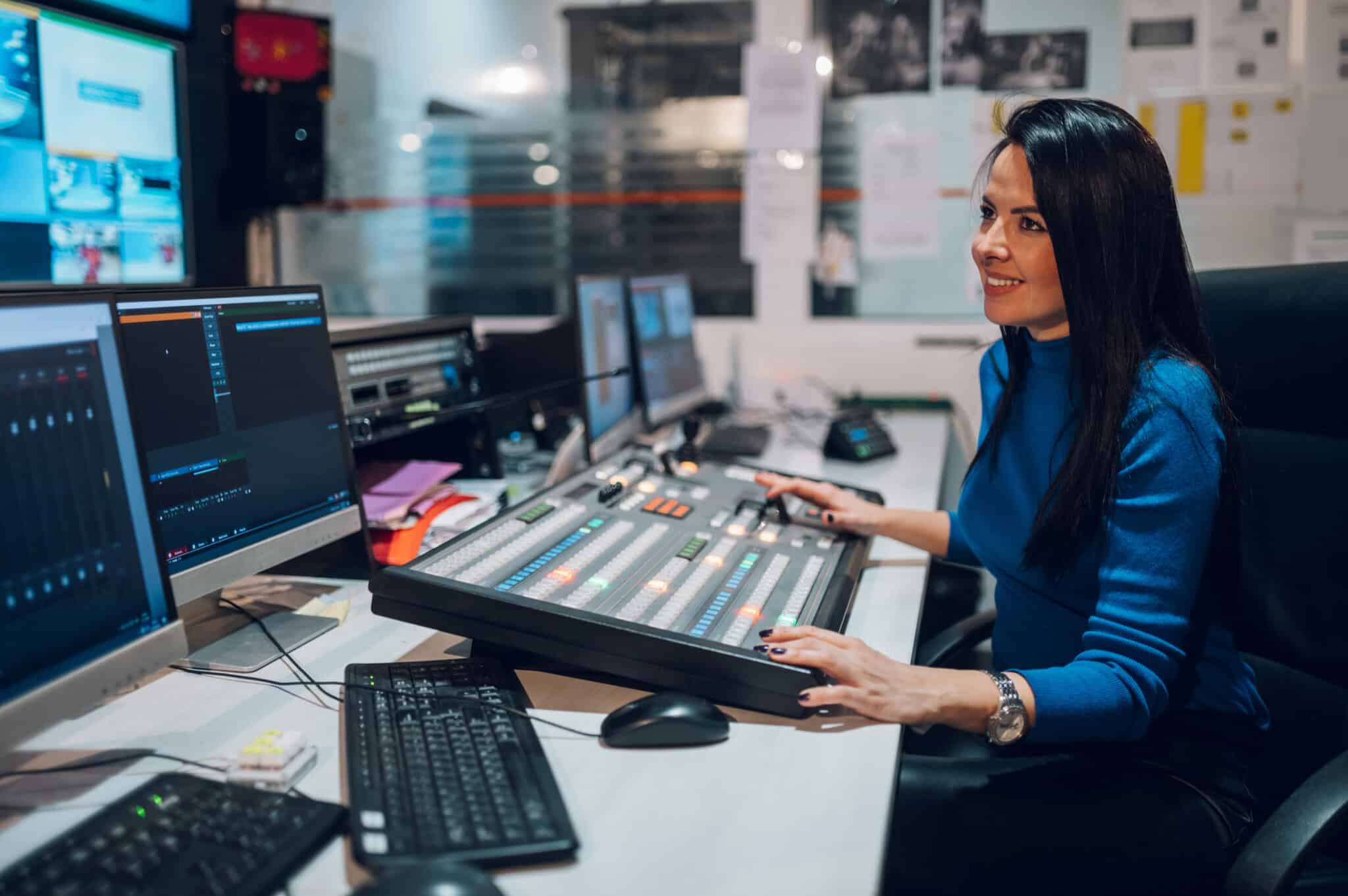 Woman works in a broadcast control room at a tv station that utilizes TV transcription services.